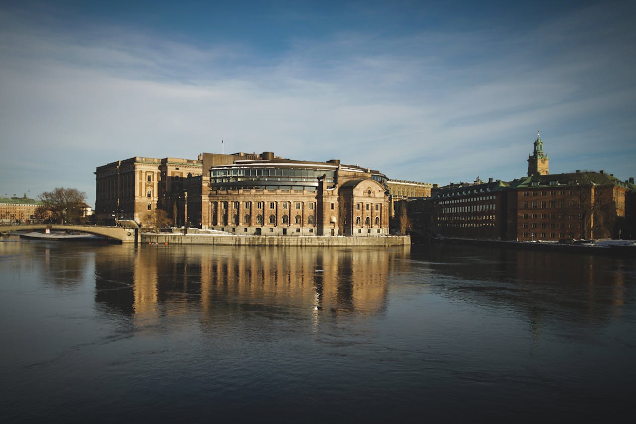 Home Stunning view of Stockholms parliament reflecting on a tranquil lake at dawn.
