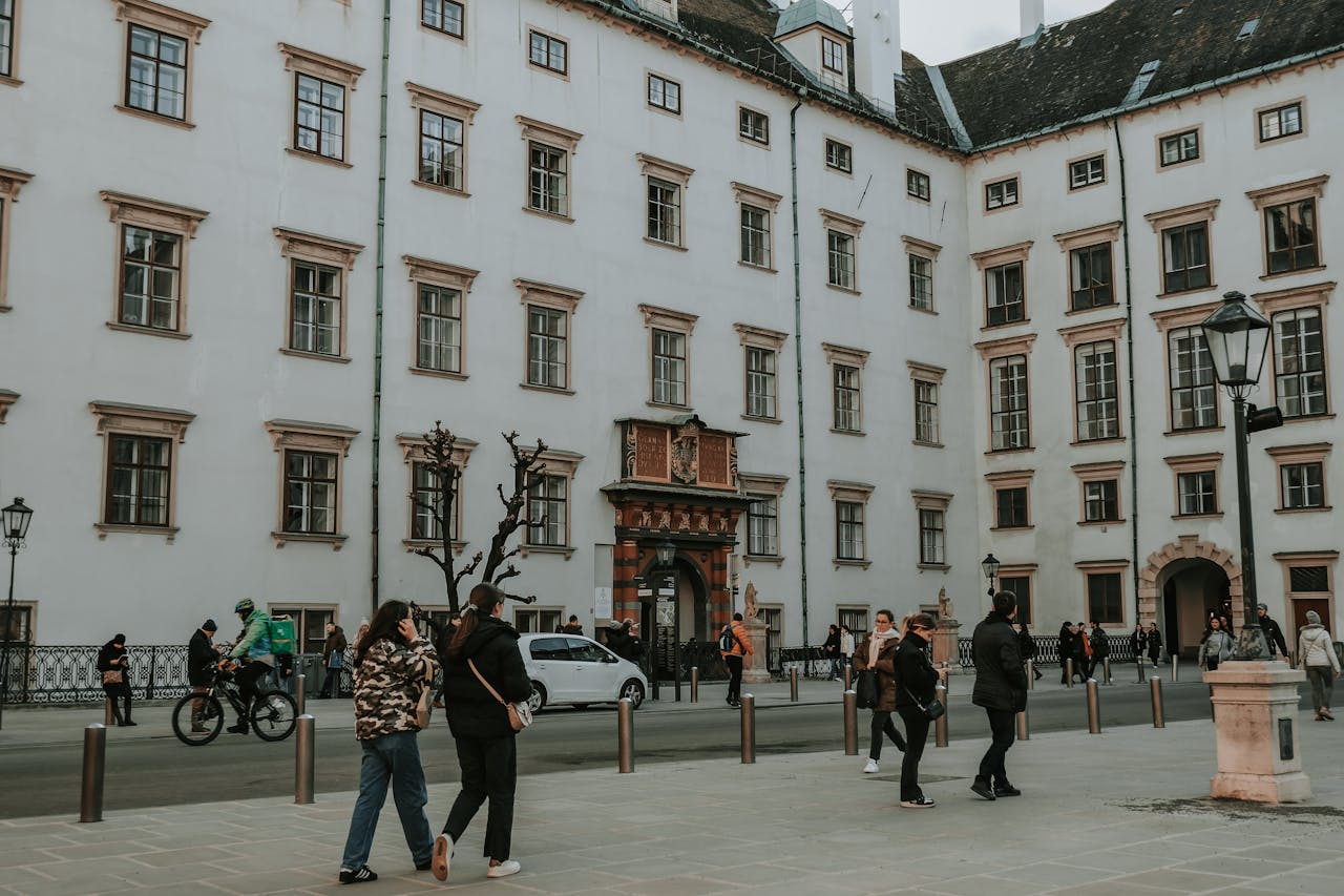 Home A lively street scene with people walking by a historic building in Vienna, Austria.